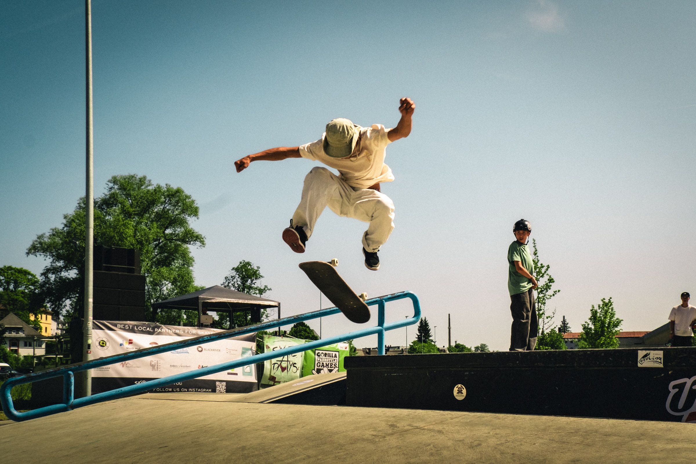 Ein Skater springt über ein Geländer, das Board unter den Füßen