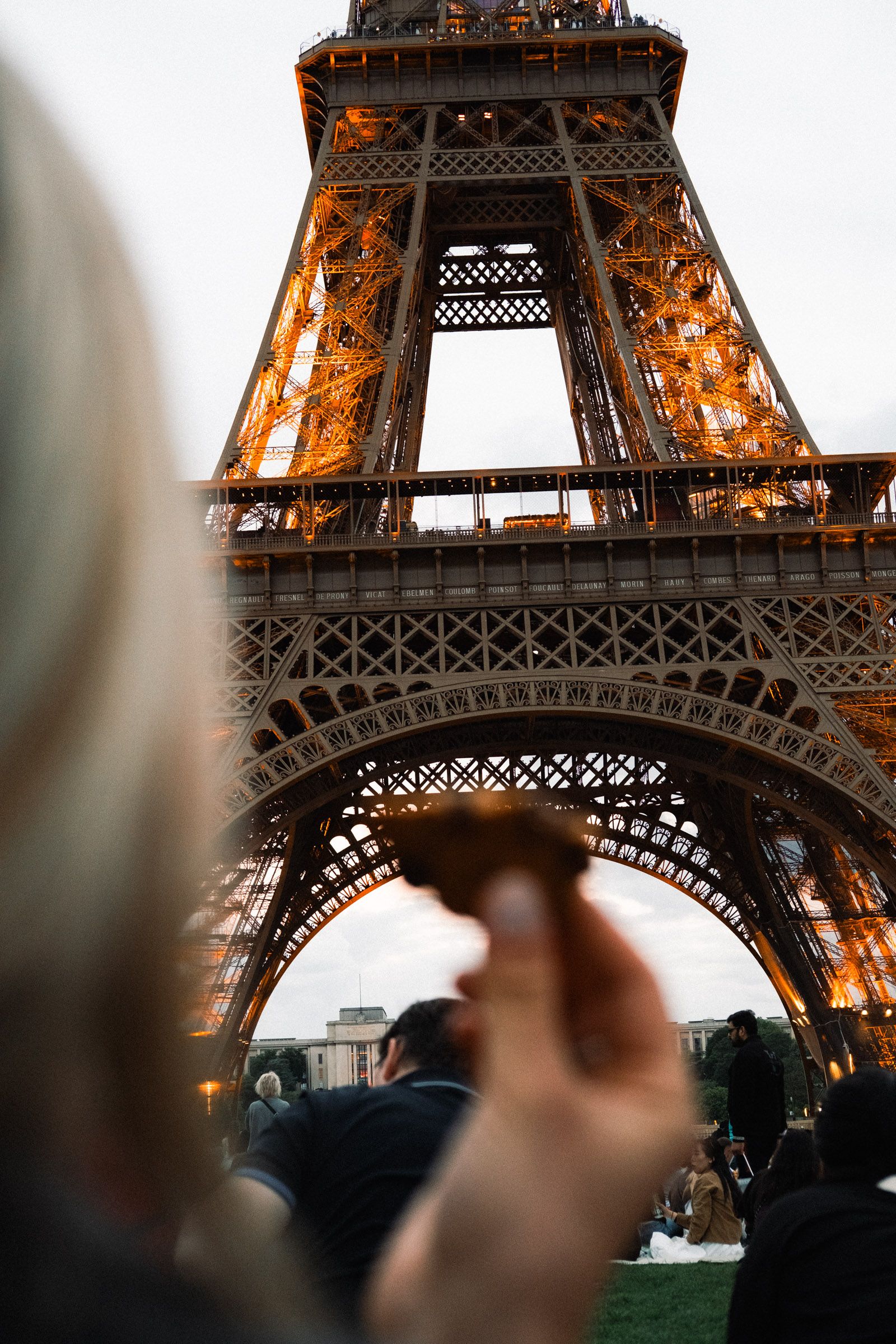 Eine Hand hält eine Crêpe vor den beleuchteten Eiffelturm